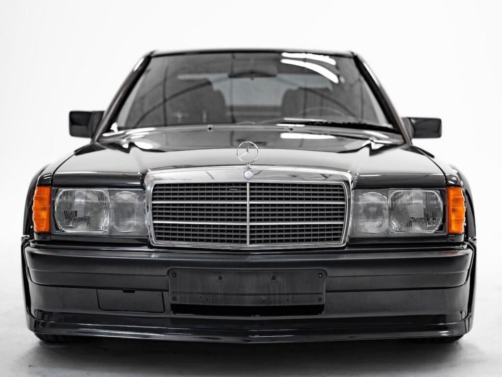 Front view of a black Mercedes-Benz W201 with chrome grille and rectangular headlights.
